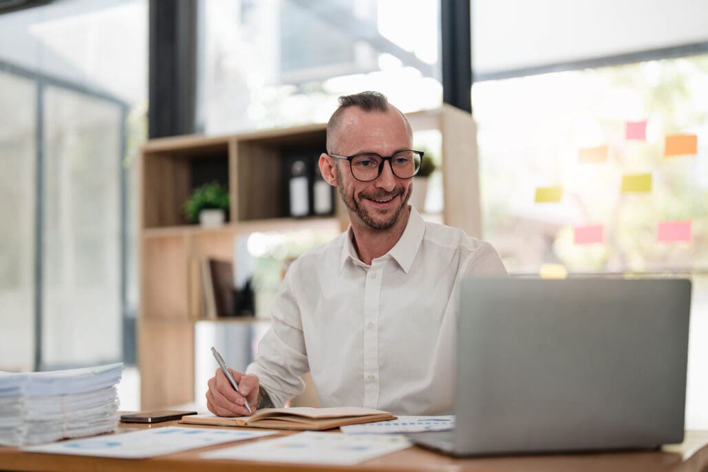 Businessman using laptop computer in office. Happy middle aged man, entrepreneur, small business owner working online.